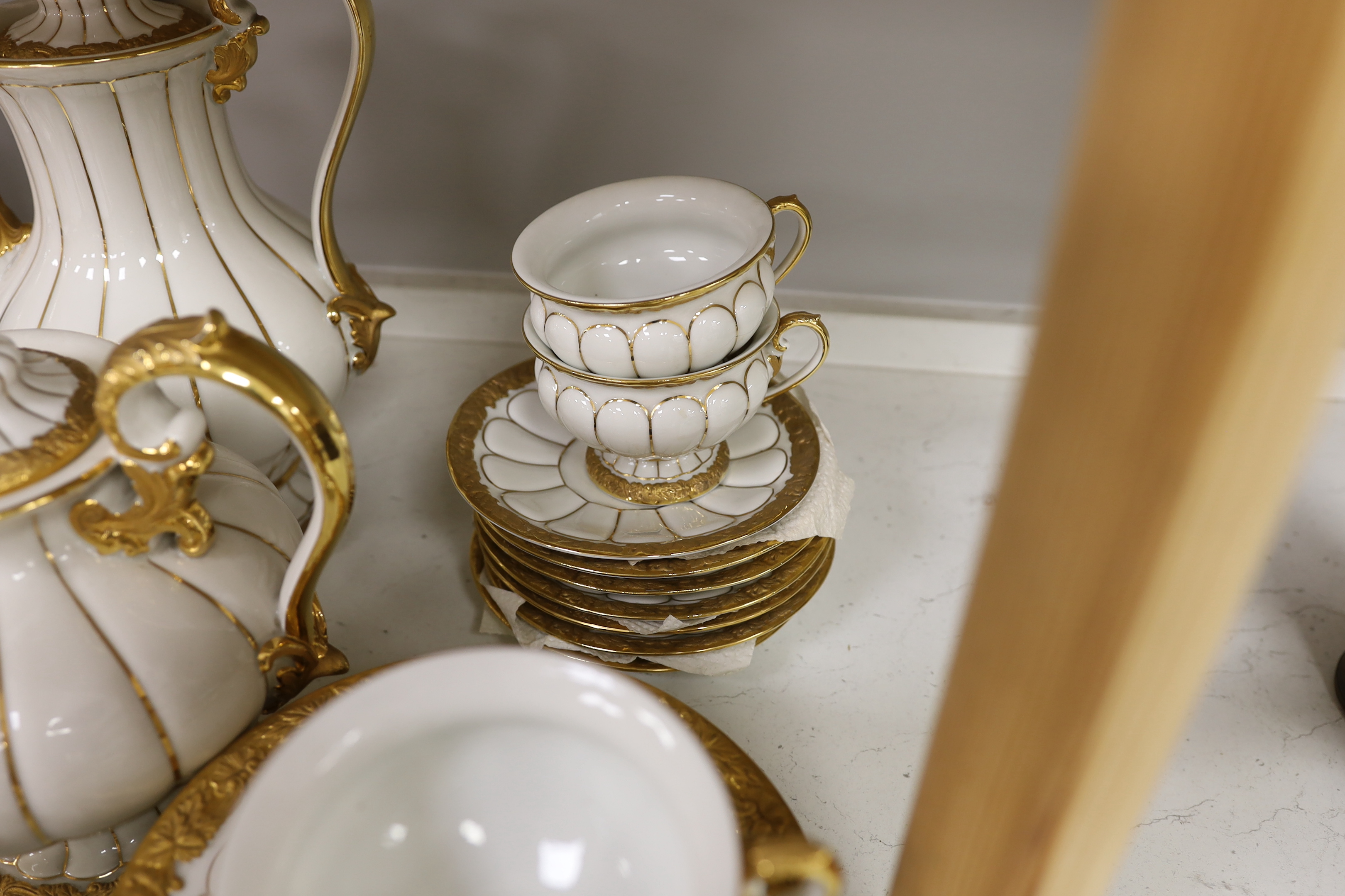 A Meissen gilt and white glazed porcelain tea service, mid 20th century, comprising a teapot, coffee pot, sugar bowl, side plates and seven cups and saucers, coffee pot 28cm